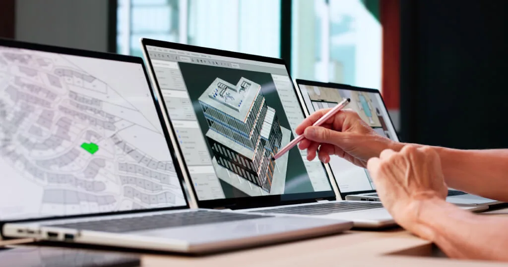 Architect using a stylus to edit a 3D building model on a laptop.